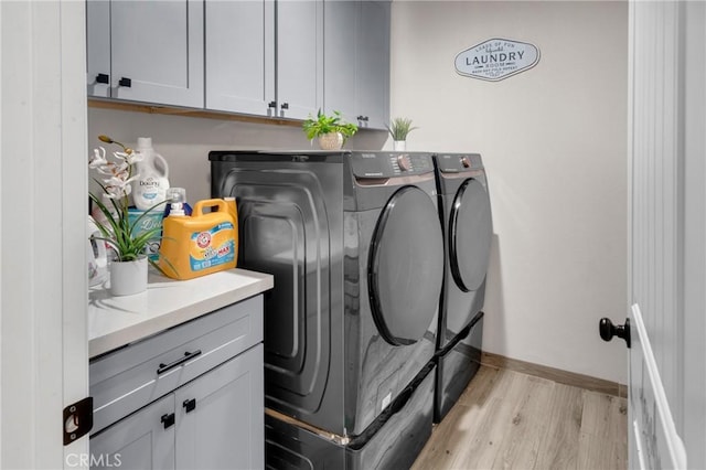 21044 Wisteria St, Apple Valley, CA 92308 - laundry room with washing machine and dryer, light wood-style flooring, cabinet space, and baseboards