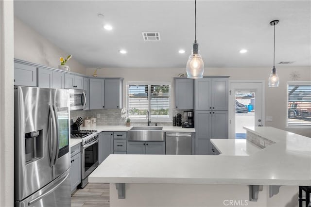 21044 Wisteria St, Apple Valley, CA 92308 - kitchen with stainless steel appliances, a sink, gray cabinetry, a kitchen bar, and tasteful backsplash