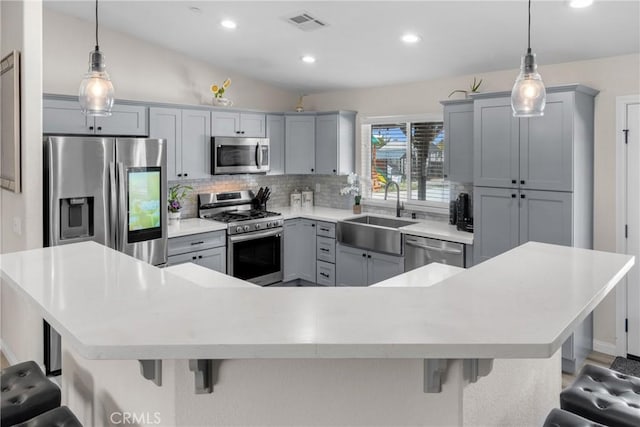 21044 Wisteria St, Apple Valley, CA 92308 - kitchen featuring appliances with stainless steel finishes, a sink, decorative backsplash, gray cabinets, and a breakfast bar