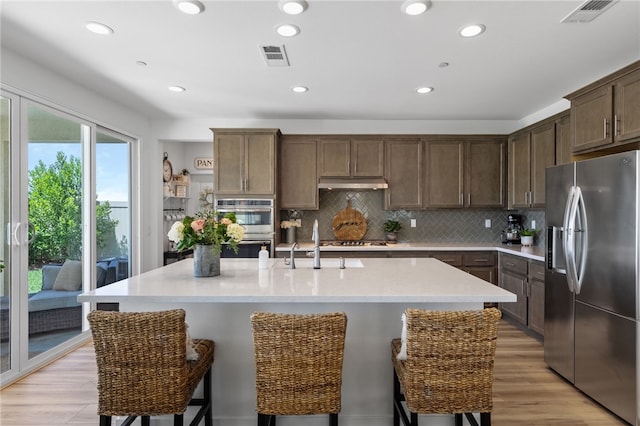 32325 Hillstone St, Temecula, CA 92591 - kitchen featuring stainless steel appliances, a sink, decorative backsplash, a breakfast bar area, and an island with sink