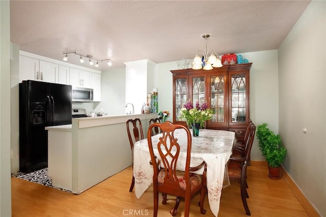 7035 Woodley Ave Unit 204, Van Nuys, CA 91406 - dining space with a chandelier, light wood-type flooring, and baseboards
