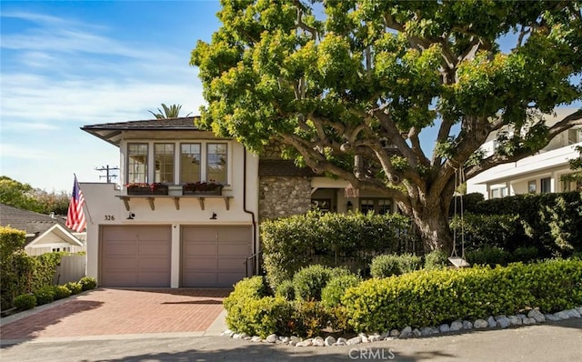 326 Ruby St, Laguna Beach, CA 92651 - view of property hidden behind natural elements featuring decorative driveway, a garage, stucco siding, and stone siding