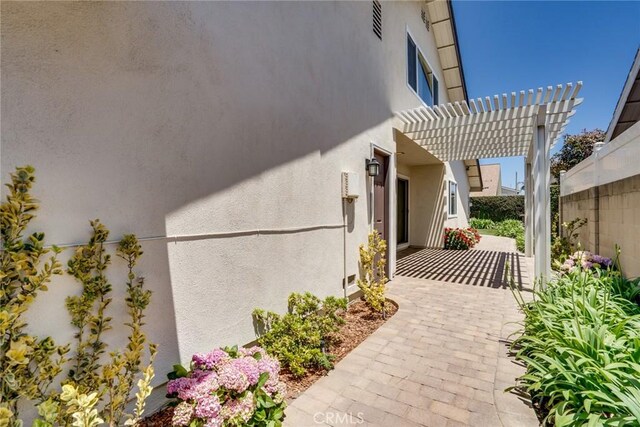 16292 Wishingwell, Huntington Beach, CA 92647 - view of side of home with a patio area, stucco siding, and a pergola