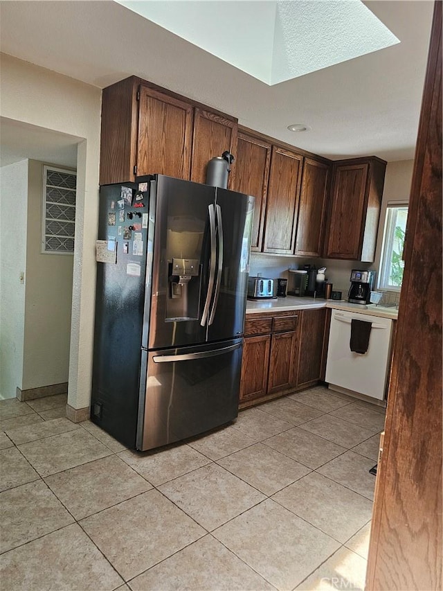 1371 Yokayo Dr, Ukiah, CA 95482 - kitchen featuring fridge with ice dispenser, white dishwasher, a skylight, light tile patterned floors, and light countertops