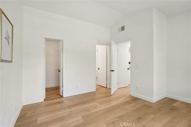 119 Gallery Way, Tustin, CA 92782 - unfurnished bedroom with a walk in closet, vaulted ceiling, light wood finished floors, baseboards, and a closet