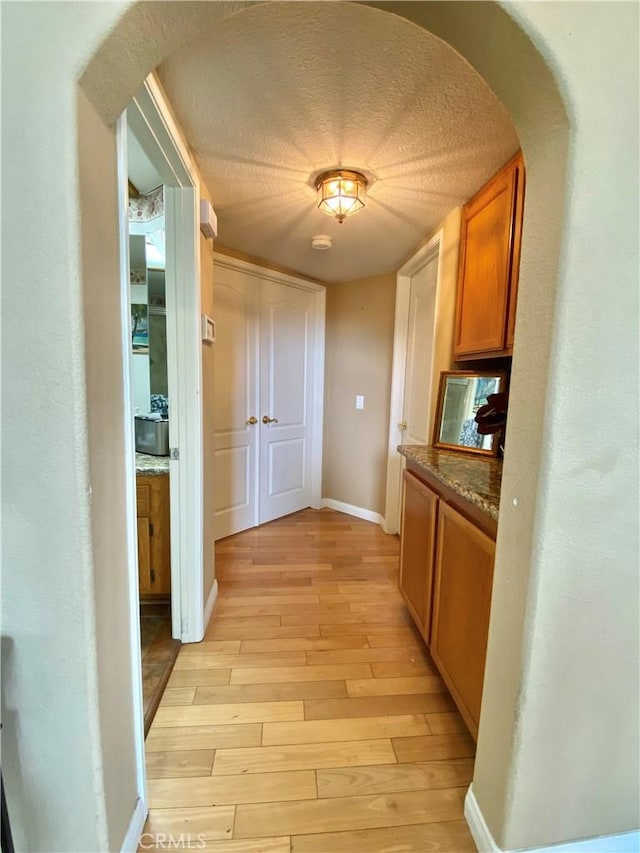 5218 Rocky Mountain Pl, Rancho Cucamonga, CA 91737 - corridor featuring arched walkways, light wood finished floors, and a textured ceiling