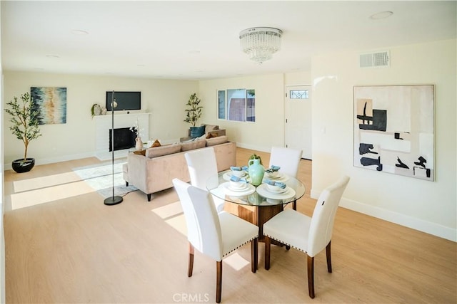 8213 Ethel Ave, North Hollywood, CA 91605 - dining area featuring light wood-style flooring, baseboards, a chandelier, and a brick fireplace