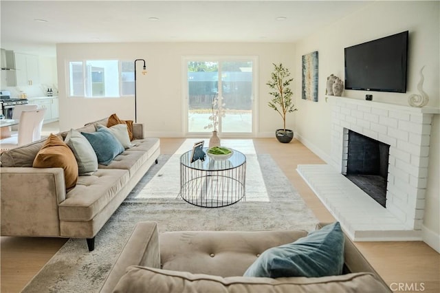 8213 Ethel Ave, North Hollywood, CA 91605 - living room featuring light wood-type flooring, a brick fireplace, and baseboards