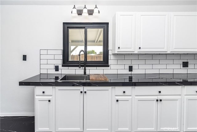 2025 Rio Vis, Needles, CA 92363 - kitchen with baseboards, white cabinetry, tasteful backsplash, dark countertops, and a sink