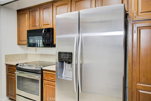 3375 Punta Alta Unit A, Laguna Woods, CA 92637 - kitchen with appliances with stainless steel finishes, brown cabinetry, and light stone countertops