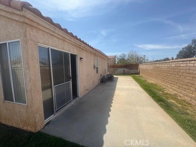 2125 Bramble Ln, Palmdale, CA 93550 - view of side of home with a fenced backyard, stucco siding, and a patio