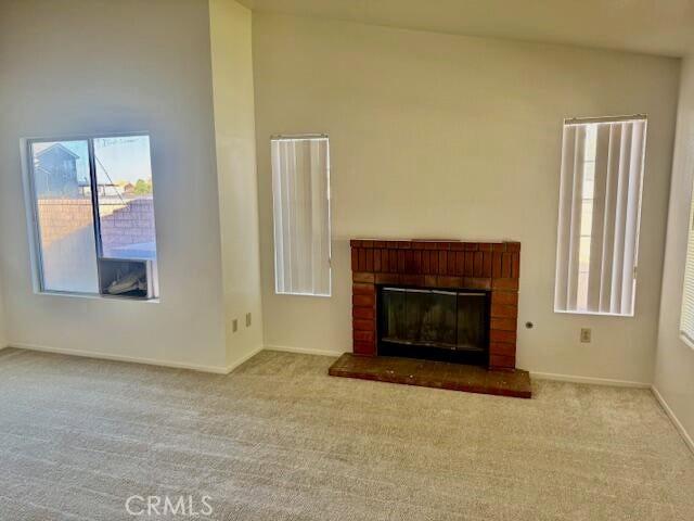 2125 Bramble Ln, Palmdale, CA 93550 - unfurnished living room with carpet flooring, a brick fireplace, and baseboards