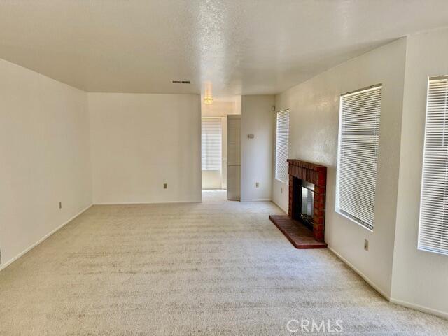 37733 Harvey St, Palmdale, CA 93550 - unfurnished living room featuring light carpet, a fireplace, and a heating unit