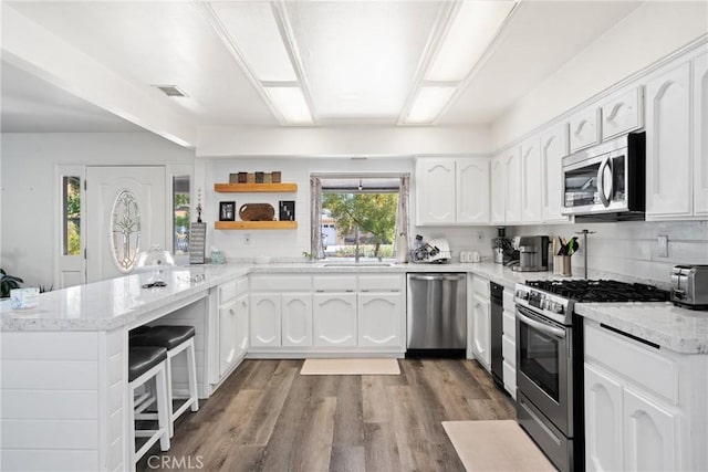 1459 Clock Ave, Redlands, CA 92374 - kitchen with stainless steel appliances, a peninsula, open shelves, white cabinets, and light stone counters