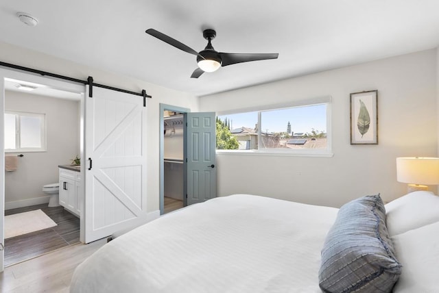 6153 Baltimore Dr, La Mesa, CA 91942 - bedroom with a barn door, multiple windows, connected bathroom, and light wood-style flooring