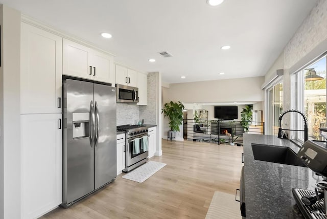 6153 Baltimore Dr, La Mesa, CA 91942 - kitchen with stainless steel appliances, a sink, dark stone counters, tasteful backsplash, and white cabinetry