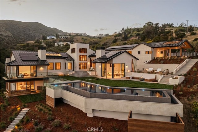 5941 Trancas Canyon Rd, Malibu, CA 90265 - back of property featuring an outdoor living space with a fire pit, a balcony, roof mounted solar panels, a standing seam roof, and stairway