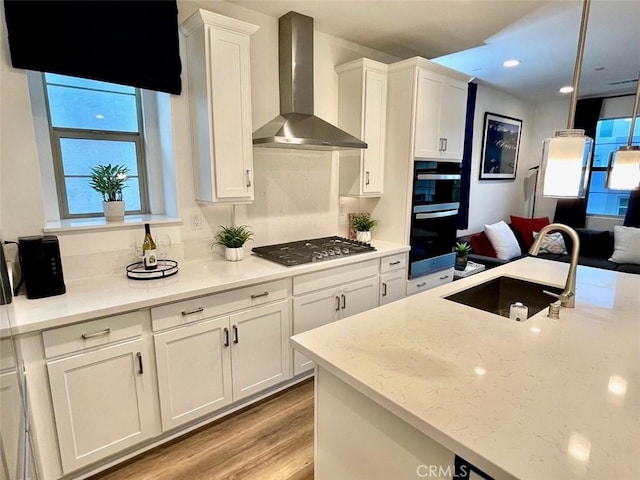181 Moonflower Rd, Rancho Mission Viejo, CA 92694 - kitchen featuring wall chimney range hood, a sink, stainless steel gas cooktop, white cabinets, and light wood-type flooring