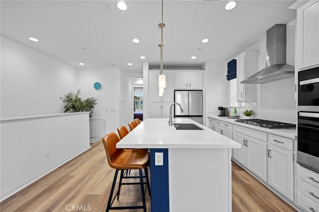 181 Moonflower Rd, Rancho Mission Viejo, CA 92694 - kitchen featuring wall chimney exhaust hood, a sink, stainless steel appliances, a breakfast bar area, and light wood finished floors