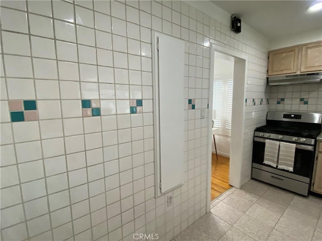 619 Center St, El Segundo, CA 90245 - kitchen with gas range, under cabinet range hood, tile walls, light tile patterned floors, and light brown cabinets