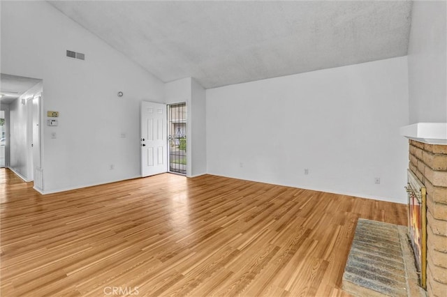 7040 Tenbury Ct, San Diego, CA 92139 - unfurnished living room featuring healthy amount of natural light, light wood-style flooring, high vaulted ceiling, and a stone fireplace