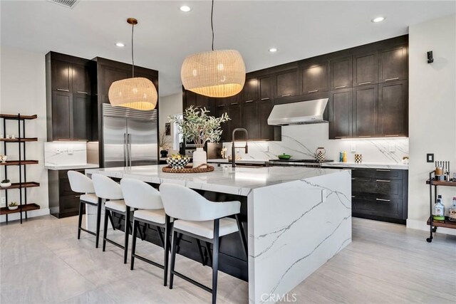 20537 W Overlook Ct, Porter Ranch, CA 91326 - kitchen with built in fridge, ventilation hood, tasteful backsplash, light stone counters, and hanging light fixtures