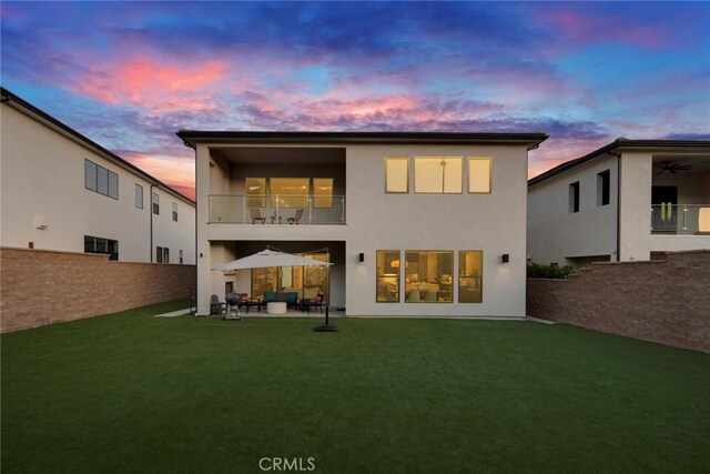 20537 W Overlook Ct, Porter Ranch, CA 91326 - back of house at dusk featuring a balcony, stucco siding, a ceiling fan, and a patio