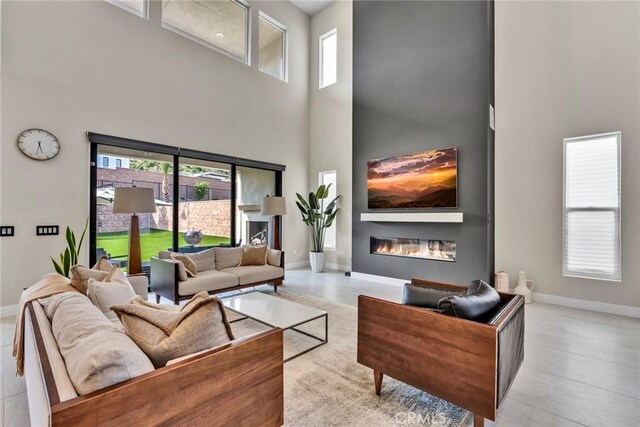 20537 W Overlook Ct, Porter Ranch, CA 91326 - living area with a high ceiling, healthy amount of natural light, baseboards, and a glass covered fireplace