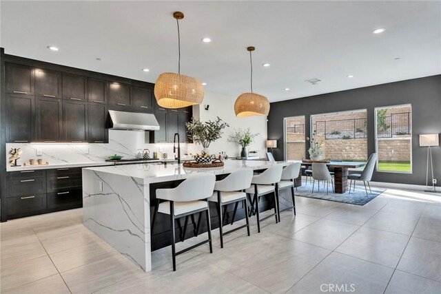 20537 W Overlook Ct, Porter Ranch, CA 91326 - kitchen with exhaust hood, recessed lighting, a center island with sink, light tile patterned floors, and light stone counters