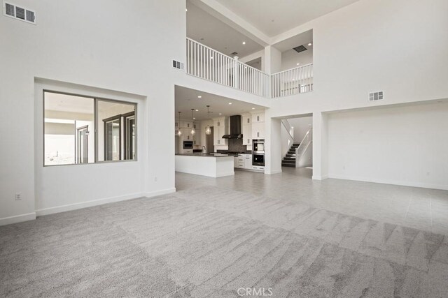 17744 Mcdowell Valley Dr, Riverside, CA 92503 - unfurnished living room with a towering ceiling, baseboards, light colored carpet, and stairway