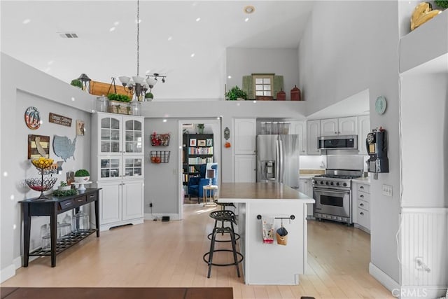 1337 Lloyd Pl, Lompoc, CA 93436 - kitchen featuring appliances with stainless steel finishes, a high ceiling, a breakfast bar area, white cabinetry, and light wood finished floors