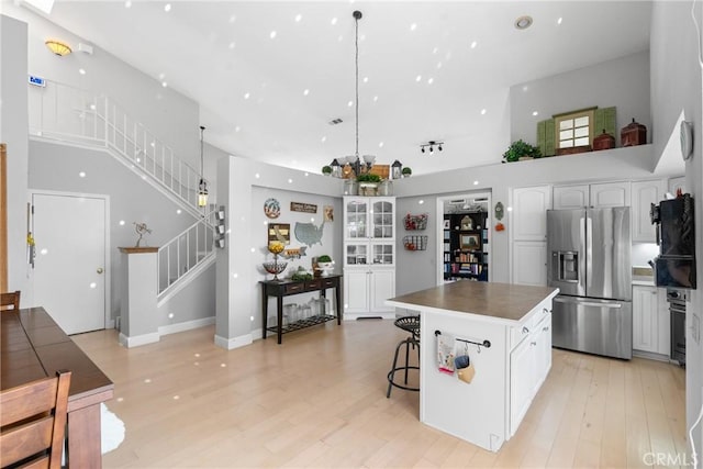 1337 Lloyd Pl, Lompoc, CA 93436 - kitchen featuring stainless steel refrigerator with ice dispenser, a towering ceiling, white cabinetry, a center island, and light wood-type flooring
