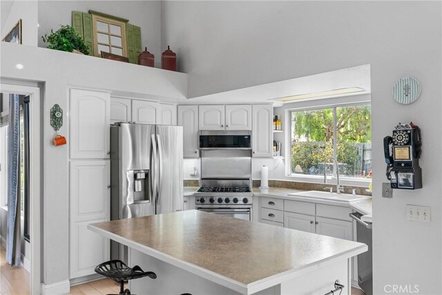 1337 Lloyd Pl, Lompoc, CA 93436 - kitchen with a sink, appliances with stainless steel finishes, a kitchen island, white cabinetry, and light wood finished floors