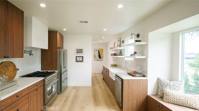 3554 S Sycamore Ave, Los Angeles, CA 90016 - kitchen featuring stainless steel appliances, a sink, light countertops, brown cabinetry, and recessed lighting