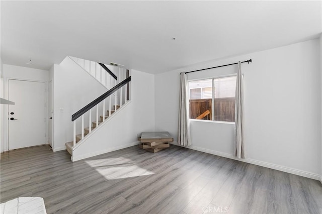 16207 Trailwinds Dr, Fontana, CA 92337 - unfurnished living room with wood finished floors and stairway