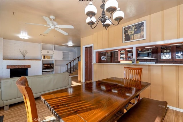 4899 Glenwood Dr, Riverside, CA 92501 - dining room featuring a decorative wall, wood finished floors, a ceiling fan, a chandelier, and stairway