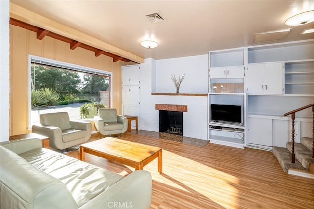 4899 Glenwood Dr, Riverside, CA 92501 - living room featuring wood finished floors, beamed ceiling, a fireplace with raised hearth, and stairs