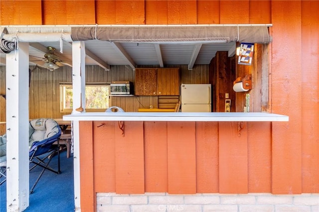4899 Glenwood Dr, Riverside, CA 92501 - kitchen featuring freestanding refrigerator, stainless steel microwave, ceiling fan, wooden walls, and carpet