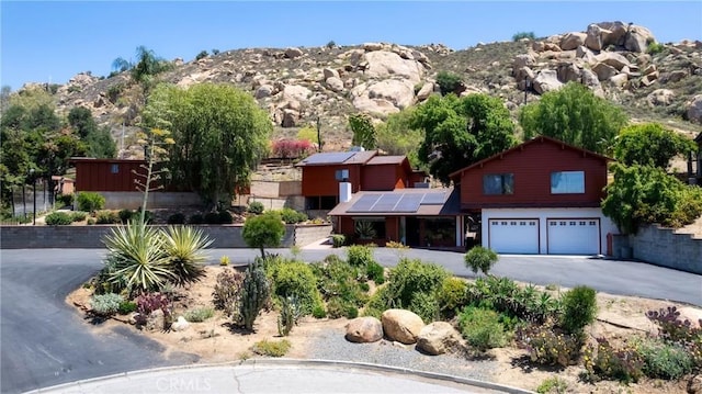 4899 Glenwood Dr, Riverside, CA 92501 - view of front of property with roof mounted solar panels, an attached garage, driveway, and a mountain view