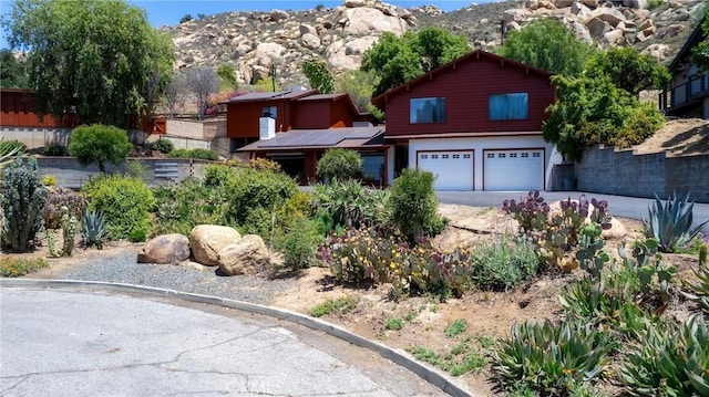 4899 Glenwood Dr, Riverside, CA 92501 - view of front of property with an attached garage, concrete driveway, a mountain view, and solar panels