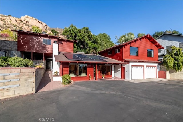 4899 Glenwood Dr, Riverside, CA 92501 - view of front of home featuring roof mounted solar panels, asphalt driveway, and a garage