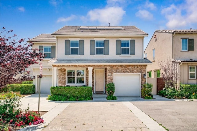 8675 Bay Laurel St, Chino, CA 91708 - view of front of house featuring a garage, driveway, roof mounted solar panels, stucco siding, and a tile roof