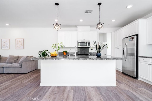 8675 Bay Laurel St, Chino, CA 91708 - kitchen with appliances with stainless steel finishes, white cabinetry, open floor plan, light wood finished floors, and dark stone countertops