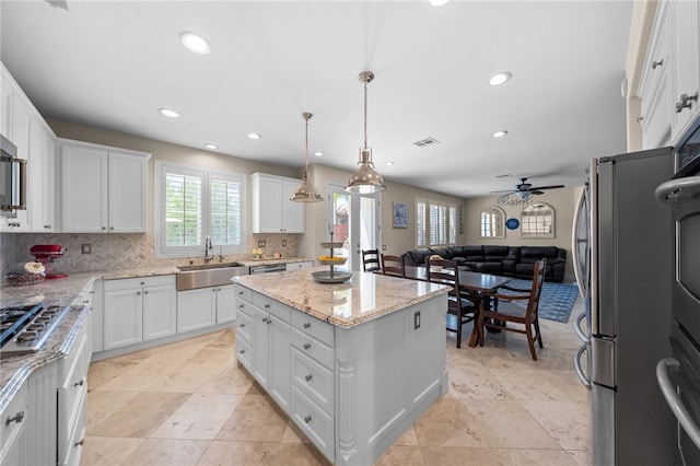 34032 Temecula Creek Rd, Temecula, CA 92592 - kitchen with appliances with stainless steel finishes, backsplash, a center island, light stone counters, and ceiling fan