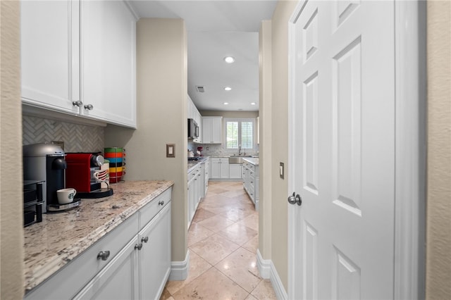 34032 Temecula Creek Rd, Temecula, CA 92592 - kitchen featuring stainless steel microwave, backsplash, light tile patterned floors, white cabinetry, and light stone counters