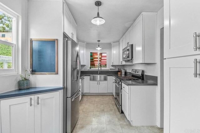 6053 Mohler St, San Diego, CA 92120 - kitchen with appliances with stainless steel finishes, a sink, dark countertops, white cabinetry, and pendant lighting