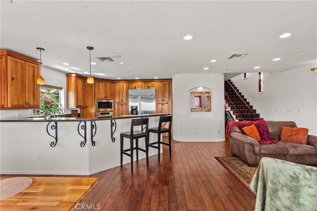 633 Sunnyhill Dr, Los Angeles, CA 90065 - kitchen featuring built in appliances, a kitchen breakfast bar, dark countertops, open floor plan, and dark wood-type flooring