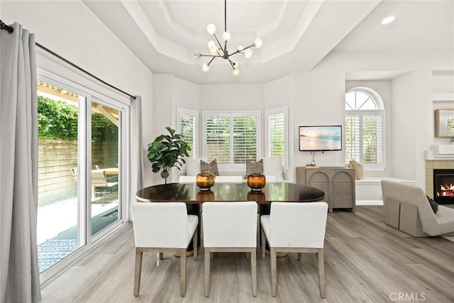 407 E Duarte Rd Unit D, Arcadia, CA 91006 - dining space featuring a raised ceiling, light wood finished floors, a chandelier, a tiled fireplace, and baseboards