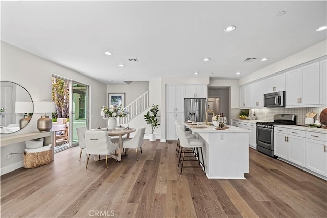 166 Borrego, Irvine, CA 92618 - kitchen with appliances with stainless steel finishes, an island with sink, white cabinets, and recessed lighting