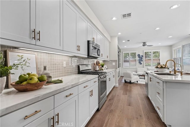 166 Borrego, Irvine, CA 92618 - kitchen with appliances with stainless steel finishes, a sink, open floor plan, wood finished floors, and recessed lighting